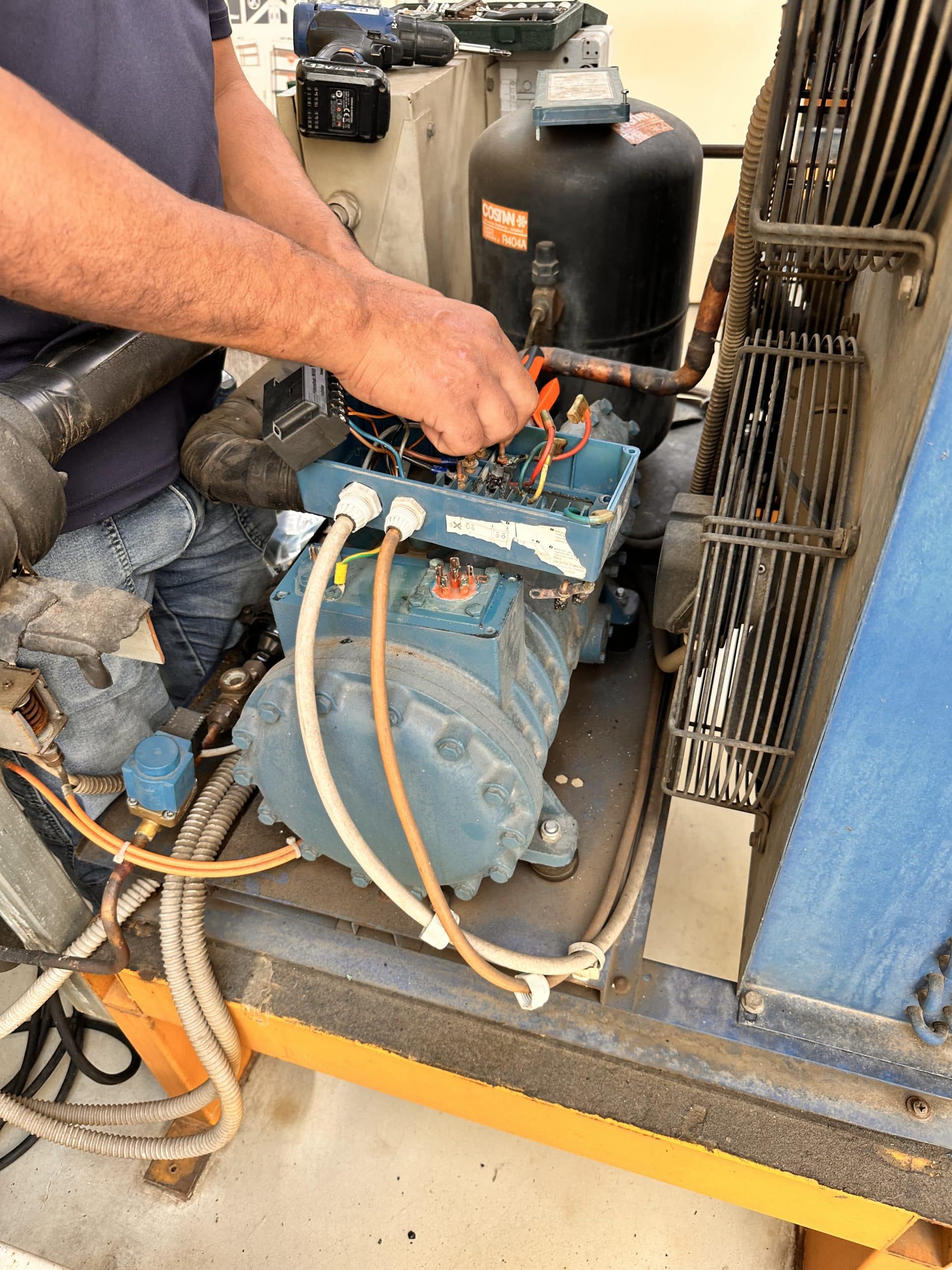 Tecnico DanorAssistance utilizza un manometro per controllare la pressione del motore di una cella frigorifera Davenia a Milano.